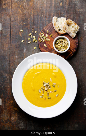 Kürbissuppe im weißen Teller auf hölzernen Hintergrund Stockfoto