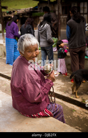 Bhutan, Nobding, alte, traditionellen Kleidung tragen Spinnen Gebetsmühle im Markt Stockfoto