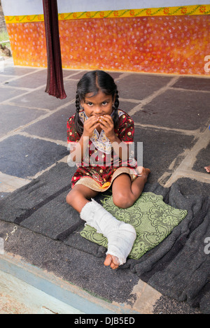 Indische Mädchen mit gebrochenem Bein Essen außerhalb ihrer indischen Dorf nach Hause. Andhra Pradesh, Indien Stockfoto