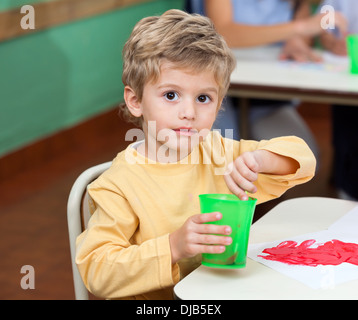 Kleiner Junge waschen Pinsel In Glas Stockfoto