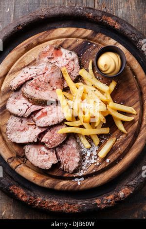 Roastbeef mit gesalzen Pommes Frites auf Schneidebrett Stockfoto