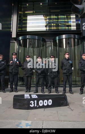 London, UK. 26. November 2013. . Polizei bewachen den Eingang von NPower HQ während ein schwarzer Sarg die Zahl der Todesfälle zugeschrieben unerschwinglich Energie- und Heizkosten als behinderte Menschen gegen Kürzungen und Brennstoff Armut Aktion Demonstarte gegen die "big six" Energieversorger zeigt. Bildnachweis: Paul Davey/Alamy Live-Nachrichten Stockfoto