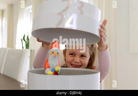 Ein kleines Mädchen öffnet das letzte Feld ihren Adventskalender am 24. Dezember, ein Weihnachtsmann aus Schokolade zu entdecken. Stockfoto