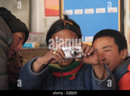 (131126)--LHASA, 26. November 2013 (Xinhua)--junge Dorfbewohner versuchen eine Kamera in Dejiu Dorf in Südwest-China Tibet autonome Region, 11. November 2013. Mehr als 600 Kilometer Weg von Lhasa, der Hauptstadt Tibets, Blick auf Dejiu Dorf Mount Qomolangma in den Südosten. Mit einer Höhe von 4.972 Metern sehen das Dorf selten grüne Bäumen um das Jahr. Jetzt gibt es 20 Familien und 118 Dorfbewohner leben in das Dorf, wo Landwirtschaft kaum entwickeln kann und die Menschen leben auf Viehzucht (nämlich Yak und Schafe) für viele Generationen. Mit Hilfe der Regierung hat das Dorf Stockfoto