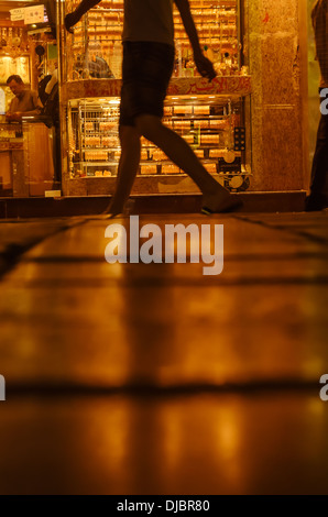 Ein Tourist geht durch die Storefront ein Juweliergeschäft in Deira Gold Souk in der Nacht. Dubai, Vereinigte Arabische Emirate. Stockfoto