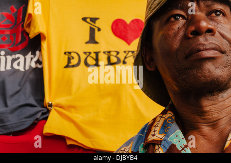 Ein afrikanischer Einwanderer Souvenir t-Shirts in Bur Dubai Souk zu verkaufen. Dubai, Vereinigte Arabische Emirate. Stockfoto