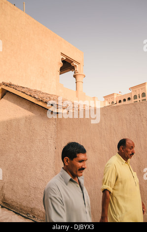 Zwei muslimische Männer zu Fuß durch die engen Straßen von Bastakiya Viertel im Stadtteil Al Fahidi historische. Dubai, Vereinigte Arabische Emirate. Stockfoto