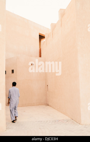Muslimischen Mann zu Fuß durch die engen Straßen von Bastakiya Viertel im Stadtteil Al Fahidi historische. Dubai, Vereinigte Arabische Emirate. Stockfoto