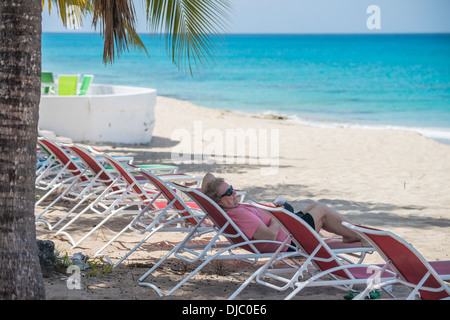 Eine 78-jährige kaukasische Frau entspannt in einem Liegestuhl am Strand in St. Croix, US Virgin Islands. Cottages by the Sea Resort. Stockfoto