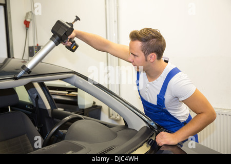 Glaser mit Pistole Auftragen von Klebstoff für Windschutzscheibe oder Windschutzscheibe Ersatz nach Steinschlag Stockfoto