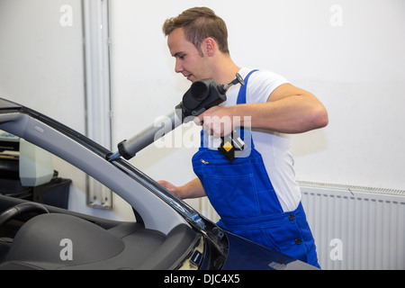 Glaser, Auftragen von Klebstoff zu Auto in der Garage für Windschutzscheibe oder Windschutzscheibe Ersatz nach Steinschlag Stockfoto