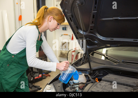 Weibliche Mechaniker Minen Kühlmittel oder Kühlflüssigkeit im Motor eines Autos Stockfoto