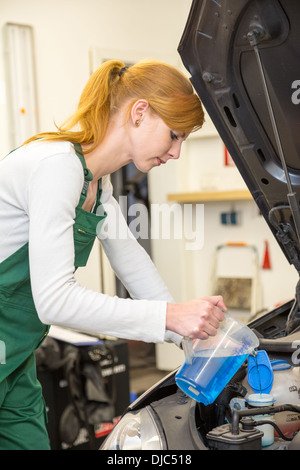 Weibliche Mechaniker Minen Kühlmittel oder Kühlflüssigkeit im Motor eines Autos Stockfoto