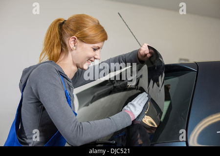 Auto-Wrapper Tönung einer Fahrzeugscheibe mit einem getönte Folie oder Film mit Heißluftpistole und Rakel Stockfoto