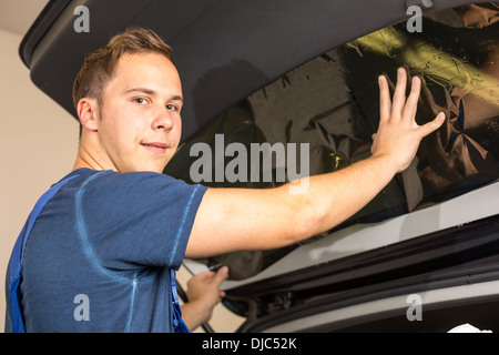 Auto-Wrapper Tönung einer Fahrzeugscheibe mit einem getönte Folie oder Film mit Heißluftpistole und Rakel Stockfoto