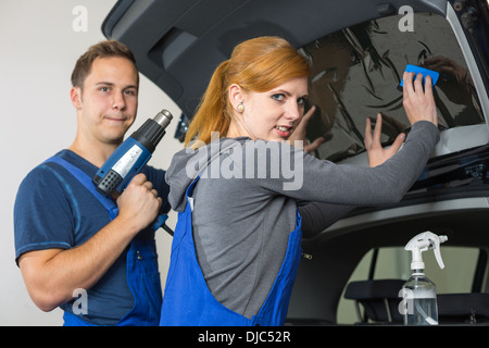 Auto-Wrapper Tönung einer Fahrzeugscheibe mit einem getönte Folie oder Film mit Heißluftpistole und Rakel Stockfoto