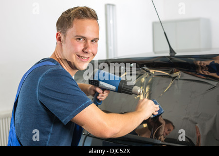 Auto-Wrapper Tönung einer Fahrzeugscheibe mit einem getönte Folie oder Film mit Heißluftpistole und Rakel Stockfoto