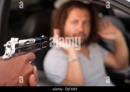 Der Fahrer eines Autos immer Carjacked mit vorgehaltener Waffe. Stockfoto