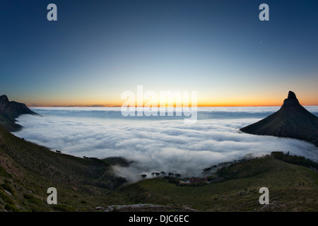 Nebel über Camps Bay und der Atlantikküste von Kapstadt, Südafrika. Löwenkopf ist sichtbar auf der rechten Seite. Stockfoto