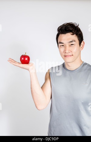 Lächelnd jungen Mann mit roten Apfel in palm Stockfoto