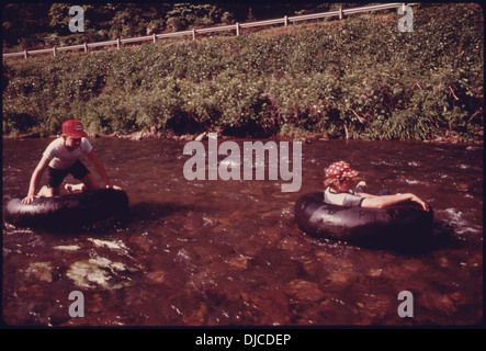 Ein Foto von zwei Jugendlichen, die in Helen, Georgia, den Chattahoochee River hinuntergleiten. Diese beliebte Sommeraktivität fängt einen Moment des Spaßes und der Entspannung auf dem Wasser ein. Stockfoto
