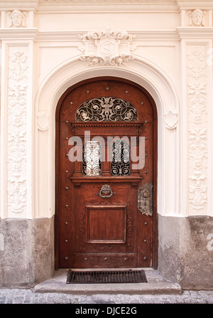 Elegante Holztür mit Bronze Griff und Dekorationen, umrahmt von ausgearbeiteten Stuck Säulen und Architrav Stockfoto