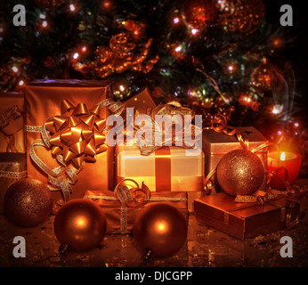 Viele verschiedene Geschenkkartons verpackt in glänzenden goldenen Papier unter geschmückter Weihnachtsbaum, Weihnachten-Überraschungen, Silvester Stockfoto