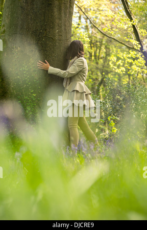 Frau versteckt sich hinter einem Baum Stockfoto