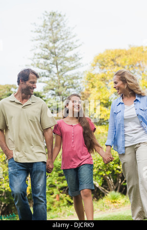 Lächelnden Eltern hand in hand gehen mit ihrer Tochter Stockfoto