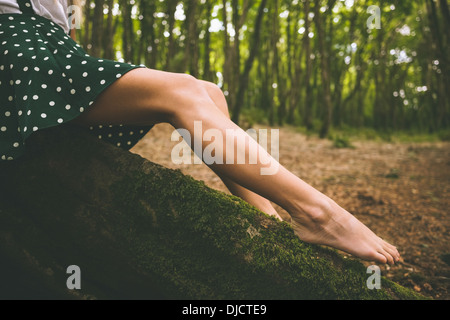 Beine einer Frau trägt einen gepunkteten Rock sitzt auf Baum Stockfoto