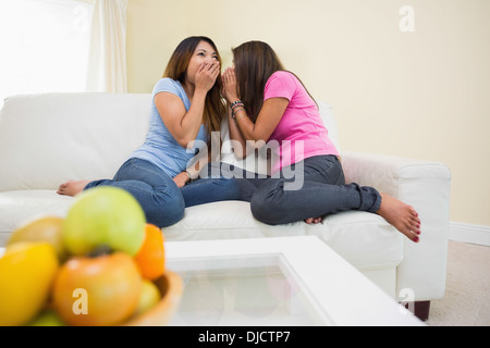 Zwei junge Schwestern tratschen beim Sitzen auf einer couch Stockfoto