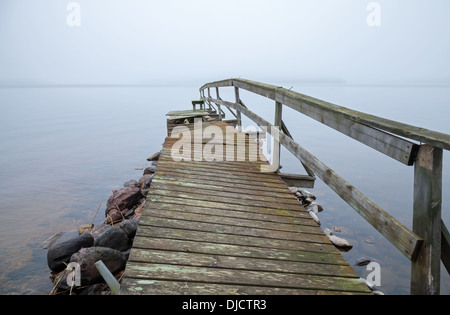 Alte hölzerne Pier Sicht auf dem See in nebligen Morgen gebrochen Stockfoto