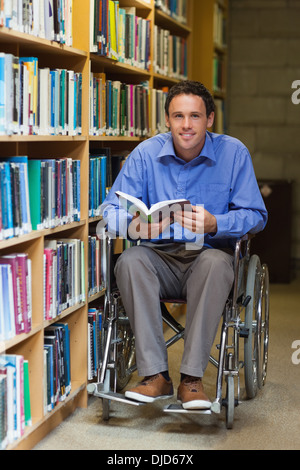 Glücklicher Mann im Rollstuhl, der ein Buch hält Stockfoto