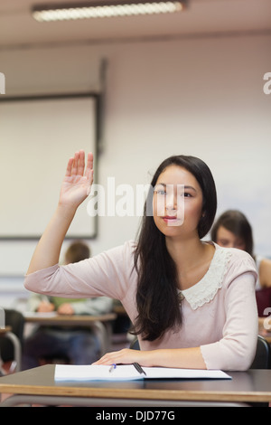 Konzentrierte sich asiatische Studentin hob ihre Hand in der Klasse Stockfoto