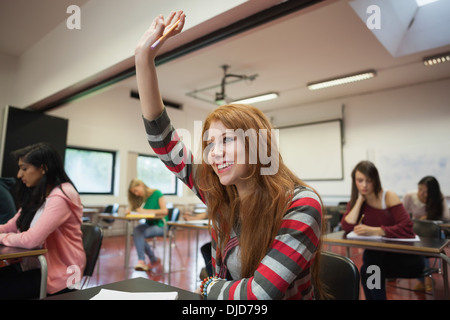 Lächelnd Studentin hob ihre Hand in der Klasse Stockfoto