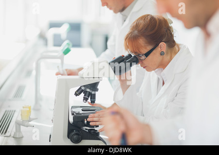 Wissenschaftlerin tragen einen Laborkittel Blick durch ein Mikroskop Stockfoto