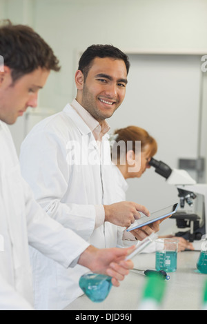 Gut aussehend männlichen Wissenschaftler hält seine weiße Tablette stehen im Labor Stockfoto