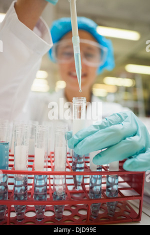 Student mit Pipette hält Reagenzglas mit blauer Flüssigkeit Stockfoto
