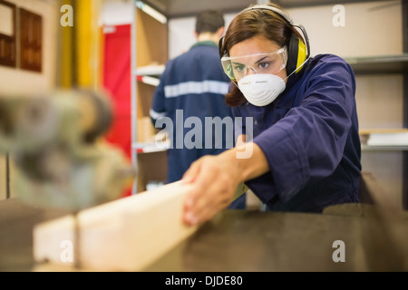 Konzentrierte sich Auszubildende tragen Sicherheitsschutz mit einer Säge Stockfoto