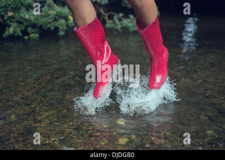 Frau in roten Gummistiefeln im Wasser springen Stockfoto