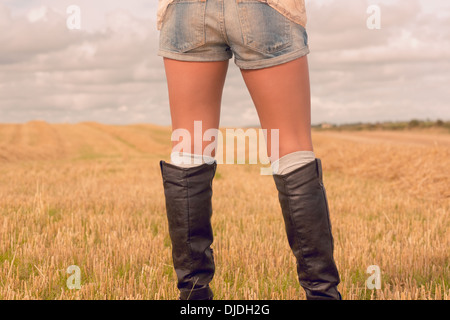 Mittleren Bereich einer Frau in Jeans-Shorts und Stiefeln auf Getreide-Feld Stockfoto