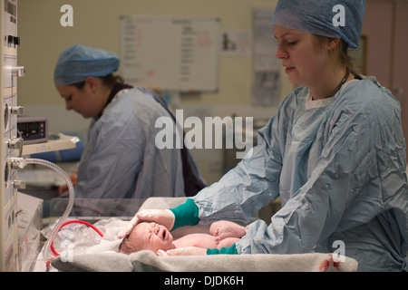 Neugeborenes Baby Boy geprüft von Krankenschwestern im Krankenhaus Mutterschaft Theater auf der Arbeit-Station im Krankenhaus, Kingston nach Themse, UK Stockfoto