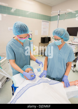 Krankenschwestern, die Sauerstoffmaske auf weibliche Patienten anpassen Stockfoto