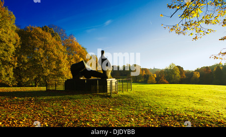 Eine Herbstszene in Kenwood: Frühmorgendliches Sonnenlicht, Herbstfarben und Henry Moores Statue / Skulptur - zweiteilige Reclining Figur Nr. 5 Stockfoto