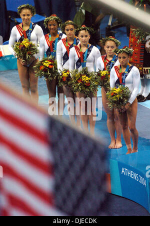 17. August 2004; Olympia Halle, Athen, Griechenland; US-Olympia-Frauen-Gymnastik-Team befasst sich mit der amerikanischen Flagge Dienstag Abend wie die Flaggen während der künstlerischen Siegerehrung Team ausgelöst werden. Die USA wurde zweite mit 113,584 Punkte auf 114,283 Punkte Rumäniens. Stockfoto