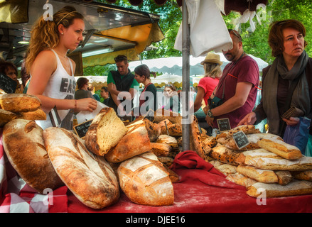 Frau, die an einem Marktstand in Lourmarin, Frankreich, handwerkliches Brot verkauft Stockfoto