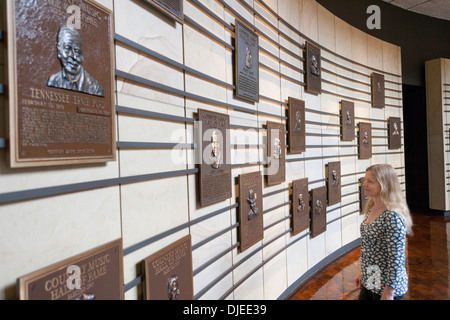 Eine Frau schaut die Plaques gewidmet Country Musikstars an einer Wand in die Country Music Hall Of Fame in Nashville, TN. Stockfoto