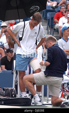 Sep 02, 2004; Flushing Meadows, New York, USA; FLORIAN MAYER von Deutschland bekommt sein Bein mit Klebeband von Trainer in seiner 2. Vorrundenspiel gegen Andre Agassi der USA bei den US Open in Flushing Meadows, NY. Mayer hatte in den Ruhestand wegen Verletzungen während des vierten Satzes mit Agassi 7-5, 6-2, 2-6, und dann 1: 0 im vierten Satz führt. Stockfoto