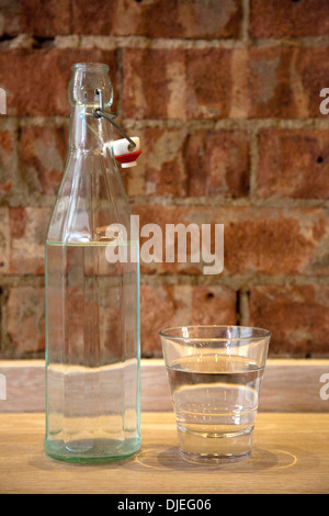 Wasserglas und Swing-Top Flasche rustikale Wand Stockfoto