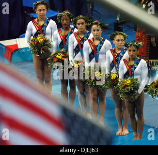 17. August 2004; Olympia Halle, Athen, Griechenland; US-Olympia-Frauen-Gymnastik-Team befasst sich mit der amerikanischen Flagge Dienstag Abend wie die Flaggen während der künstlerischen Siegerehrung Team ausgelöst werden. Die USA wurde zweite mit 113,584 Punkte auf 114,283 Punkte Rumäniens. Stockfoto